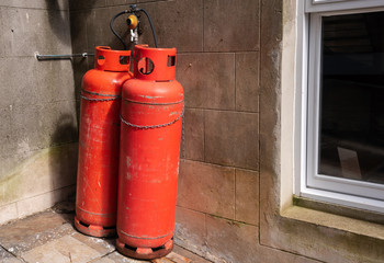 Red propane cylinders near the external stone wall of an old house