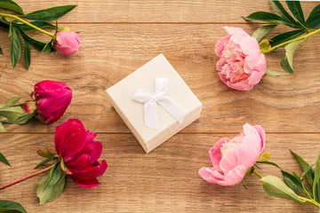 Gift box on wooden boards with peony flowers.