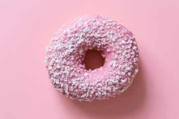 Fototapeta na wymiar Pink frosted donut sprinkled with crystal sugar isolated on pink background from above.