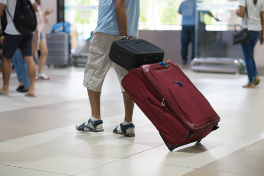 Traveler pulling suitcase in airport terminal.