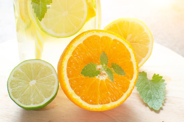Fototapeta na wymiar Lemonade of orange, lemon, lime and mint on the background of the contour sunlight.