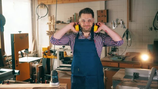 Working joiner smiles at camera, standing in a workshop. Carpenter working.