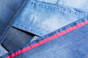 Background and texture of lot of different blue jeans, some with red stripe