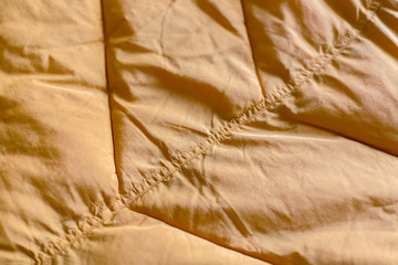 Close-up on dirty yellow puffer jacket texture. The seam on jacket close up