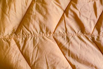 Close-up on dirty yellow puffer jacket texture. The seam on jacket close up