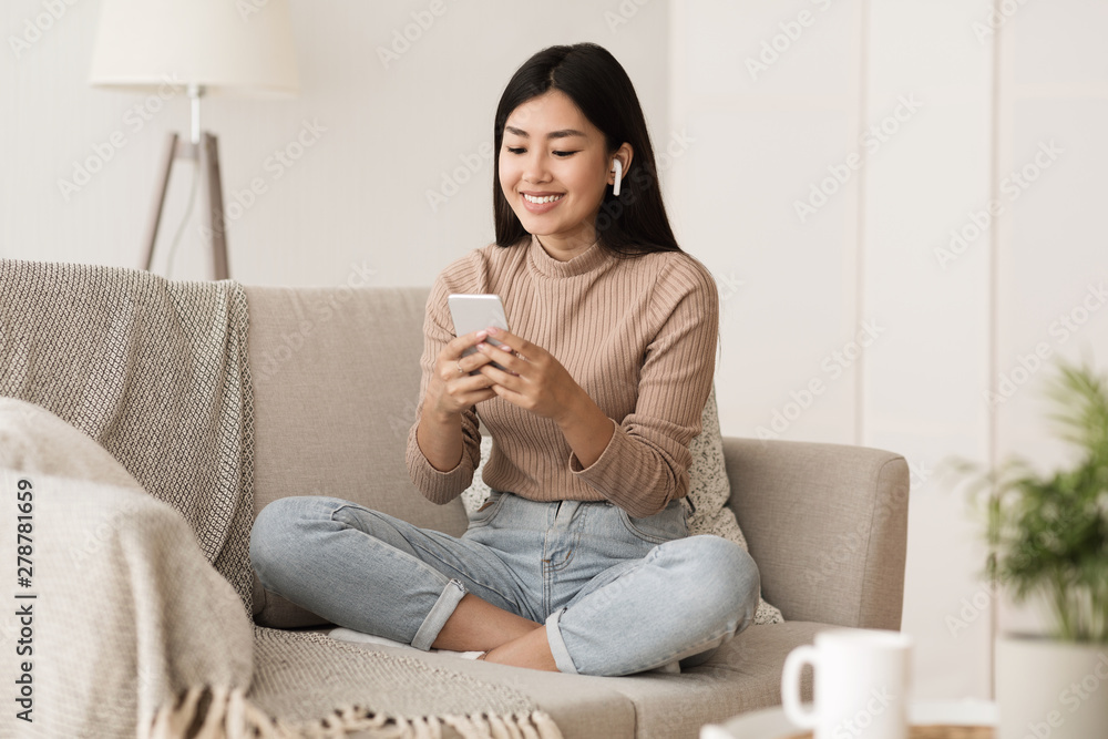 Wall mural Student Girl Relaxing on Couch at Home with Phone