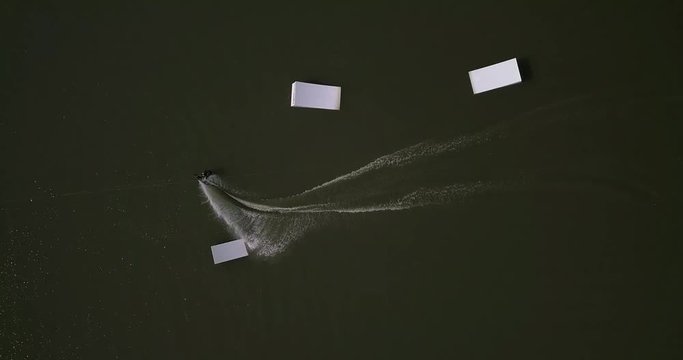 Aerial shot of a cableway in a lake with a wakeboarder making turns and tricks. Sportsman grinding and rotating on a funbox. Girl wakeboarding in wake park. Sport time summer concept.