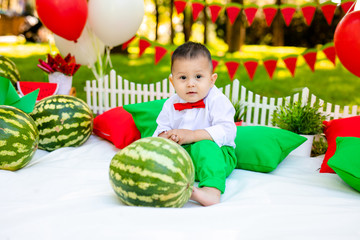 Fototapeta na wymiar Happy child with big red slice of watermelon sitting on green grass in summer park. Healthy eating concept