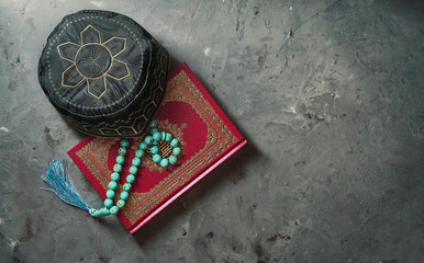 Islamic Book Koran with rosary and pray hat on grey slate background. Islamic concept with copy space, top view