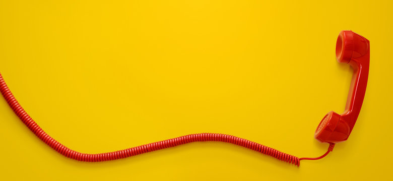 Red vintage telephone handset isolated on yellow background with copy space