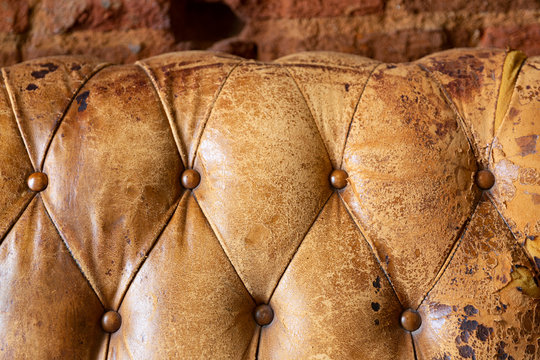 Detalle y textura de respaldo de un sofá chester viejo y desgastado en color marrón