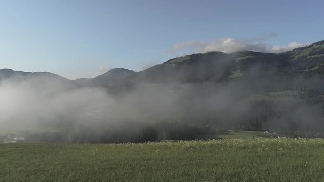 Foggy morining in green mountains over rural country.
