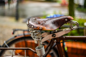 Berlin, Germany - July 13, 2019: Close-up of an old, cracked leather saddle of a bicycle on which the raindrops gather.
