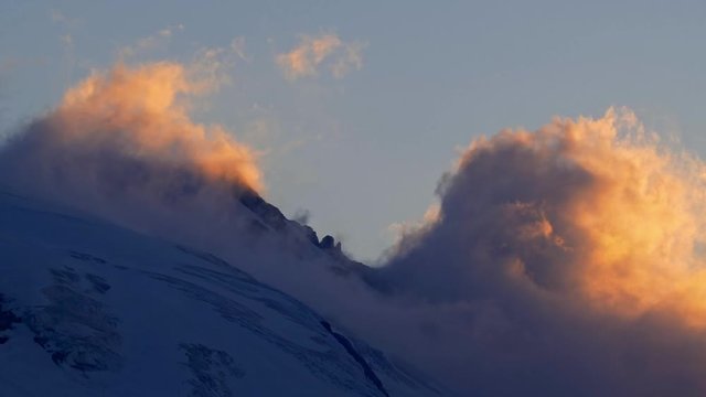 Clouds above the mountain peak at sunset timelapse