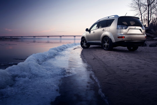 Saratov, Russia - November 27, 2014: Car Mitsubishi Outlander is standing on ice coast at winter sunset