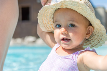 Baby girl with hat smile in swimming pool.