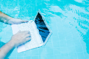 Male hands with a laptop working underwater. The concept of obstruction in the work. Blur Abstract Background.