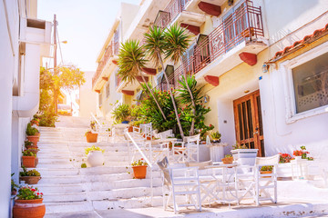 Outdoor cafe on a traditional greek street with flowers and white architecture, Crete island, Greece
