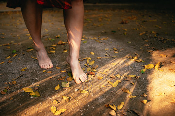 Young woman walking barefoot through autumn leaves