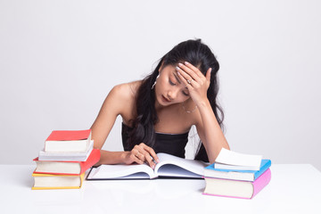 Exhausted Young Asian woman read a book with books on table.