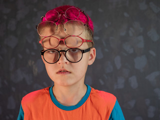 Fototapeta na wymiar Photo of funny kid with many pairs of glasses on face
