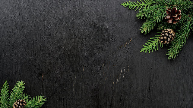 Christmas Fir tree branches and pine cones on a black wooden board