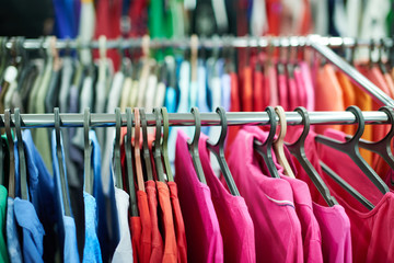 Multicolor clothes hanging on hangers in a second-hand store