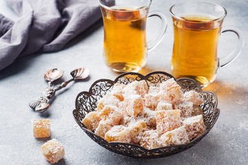 Turkish delight with hazelnut in carved metal bowl and tea in glass Cup, selective focus