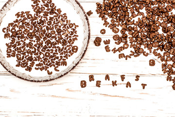 dry cereal breakfast laid out by the word breakfast on a white wooden background.