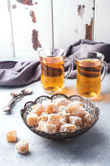 Turkish delight with hazelnut in carved metal bowl and tea in glass Cup, selective focus