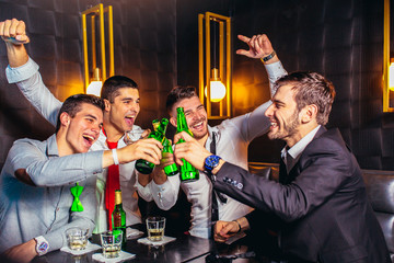 Group of young men toasting at a nightclub - obrazy, fototapety, plakaty