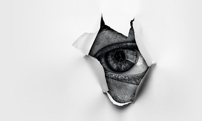 Eye in a hole of torn paper