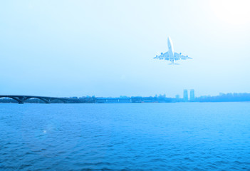 Plane over the river. Evening landscape and sun.