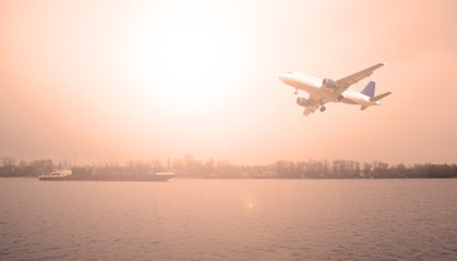 Airliner flying over the river. The evening sunset.