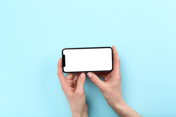 Smartphone in female hands on blue background