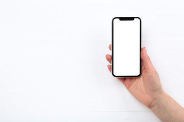 Smartphone in female hand on wooden background