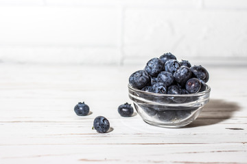 Blueberries with water drops on a wooden white background.