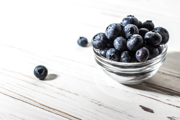 Blueberries with water drops on a wooden white background.