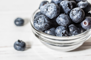 Blueberries with water drops on a wooden white background.