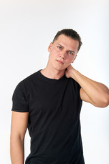 Fototapeta premium Portrait of attractive young stylish confident man wearing a black cotton short-sleeved T-shirt posing in studio. Studio shot on a white background.
