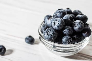 Blueberries with water drops on a wooden white background.