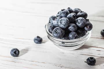 Blueberries with water drops on a wooden white background.