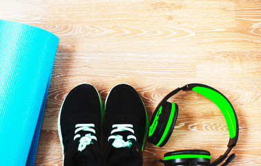 blue yoga and sports Mat, black sneakers with green laces, headphones,