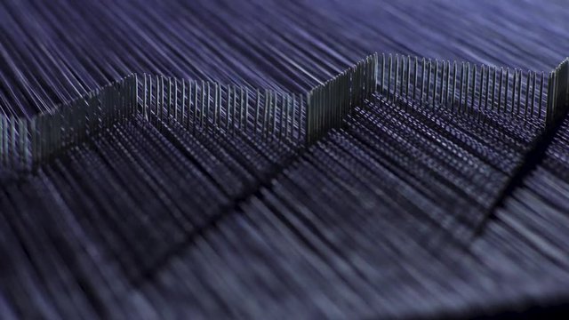 Close up of denim threads being carefully sorted by a machine at high-speed in a garment factory.