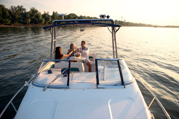 Friends on a boat in sunset drinking champagne