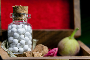 close up view of homeopath white sugar ball medicine in wooden old box wild flower wild, fruit bud in dark background
