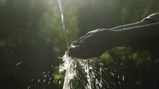 Water pouring in ederly farmer's hand, nature background, environment issues. Aqua pouring splash in hand. (Drought / Scarcity). Lack of fresh drinking water resources, water usage. Hands water splash