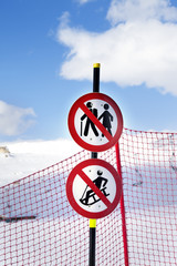 Snowy ski slope, fence and two prohibitory traffic sign on ski resort