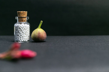 Natural Homeopathy - homeopath medicine with wild fruit and flower buds on dark background