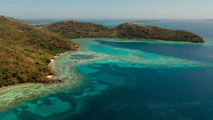 aerial view tropical island Bulalacao with blue lagoon, coral reef and sandy beach. Palawan, Philippines. Islands of the Malayan archipelago with turquoise lagoons.